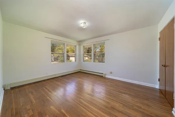 an empty room with wooden floor and windows