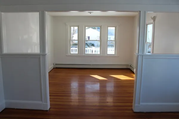 a view of empty room with wooden floor and fan