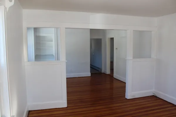 a view of an empty room with wooden floor and closet