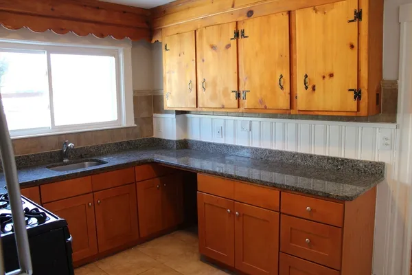 a kitchen with stainless steel appliances granite countertop wooden cabinets a sink and a large window