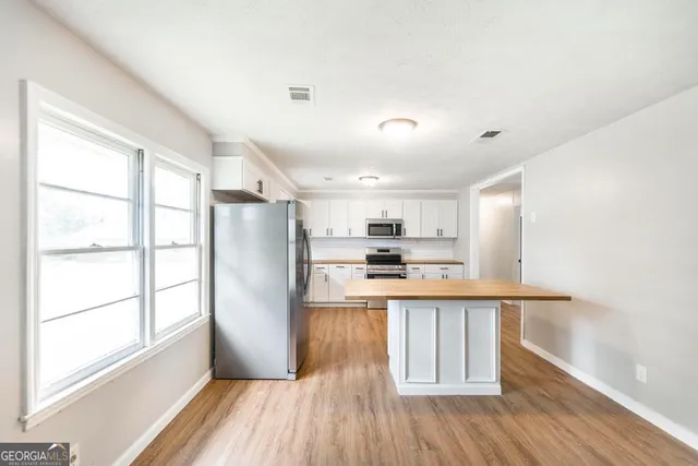 a kitchen with stainless steel appliances a refrigerator a sink dishwasher a stove and white countertops with wooden floor