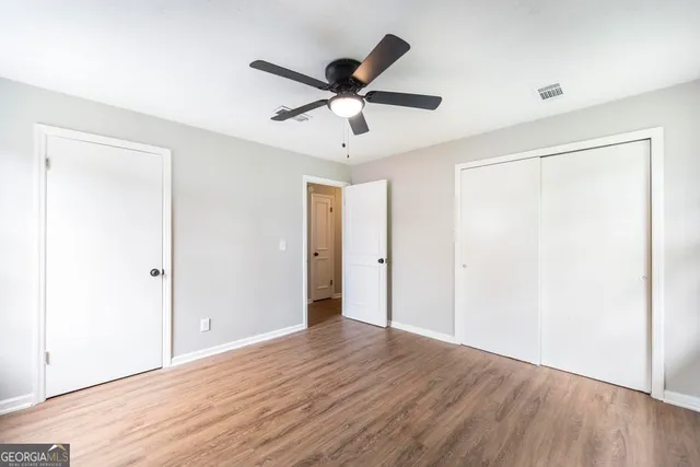 a view of empty room with wooden floor and ceiling fan