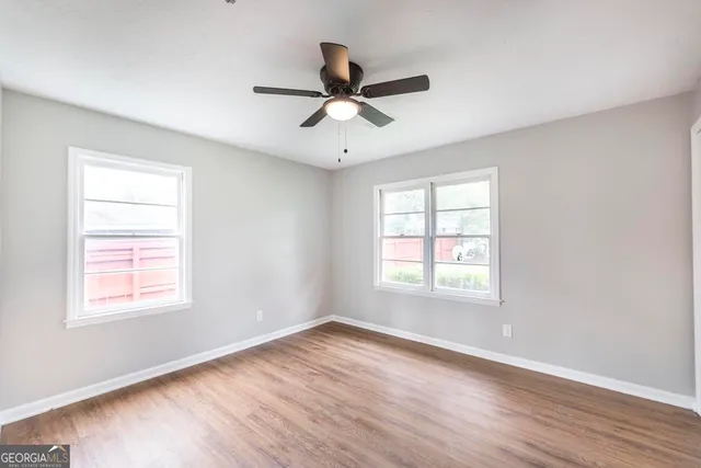 a view of empty room with wooden floor and fan
