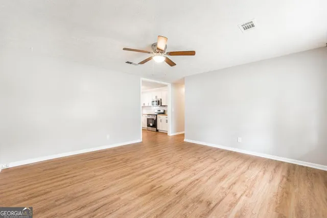 a view of a room with wooden floor and a ceiling fan