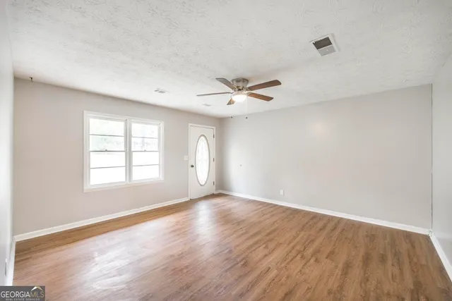 an empty room with wooden floor and windows