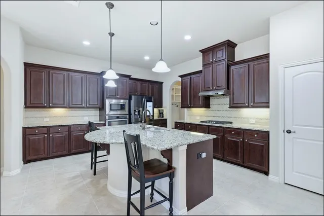 a kitchen with stainless steel appliances kitchen island granite countertop a sink a center island a stove and a cabinets