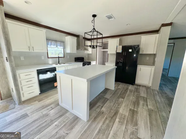 a kitchen with a sink a stove cabinets and a wooden floor