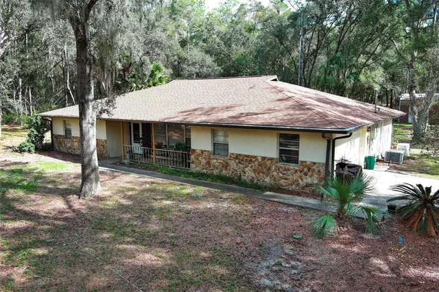 a view of a house with a yard and large tree