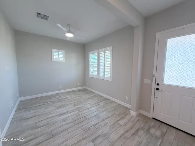 an empty room with wooden floor and windows