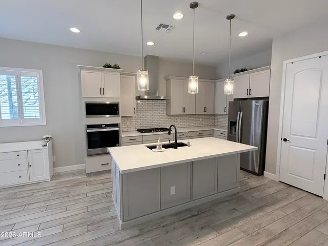 a kitchen with a sink a center island stainless steel appliances and cabinets