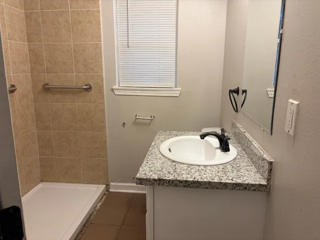 a bathroom with a granite countertop sink a toilet and shower