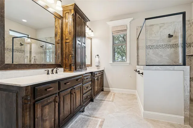 a spacious bathroom with a double vanity sink a mirror and a shower