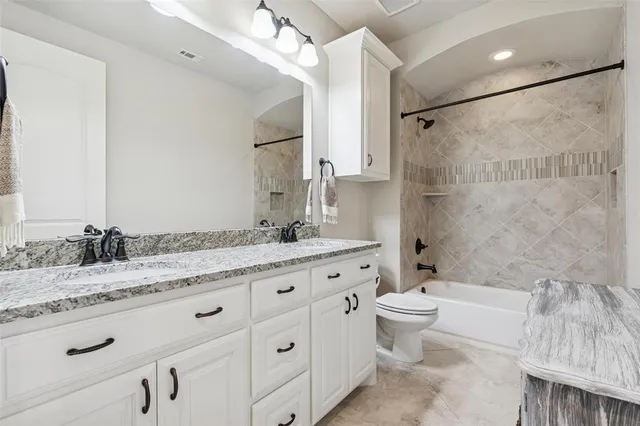 a bathroom with a granite countertop sink a toilet a mirror and shower