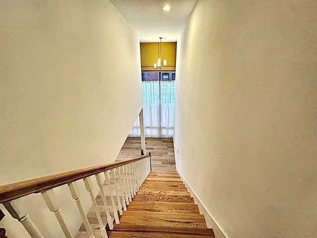 a view of a hallway with wooden floor and a bathroom