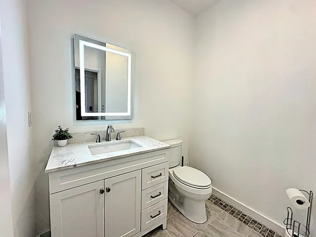 a bathroom with a granite countertop toilet a sink and a mirror