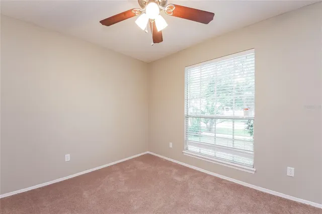 an empty room with a window and a fan