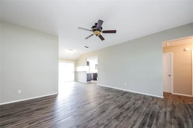 a view of a room with wooden floor ceiling fan and window