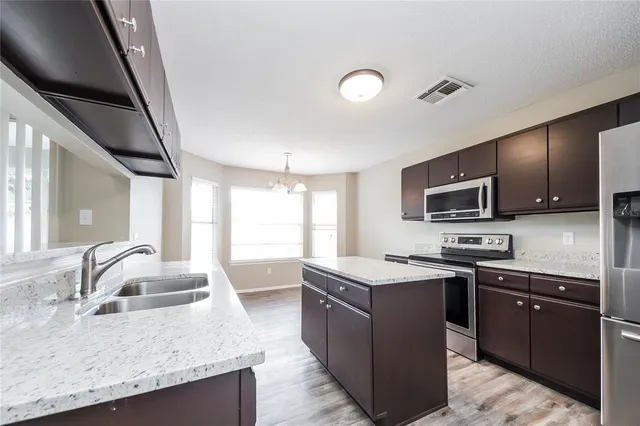 a kitchen with stainless steel appliances granite countertop a sink stove and microwave