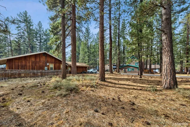 a backyard of a house with wooden fence and large trees