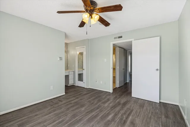 an empty room with wooden floor and a ceiling fan