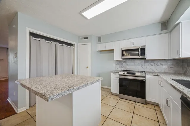 a kitchen with stainless steel appliances granite countertop a stove a sink and a microwave