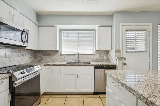 a kitchen with granite countertop cabinets stainless steel appliances a sink and a window
