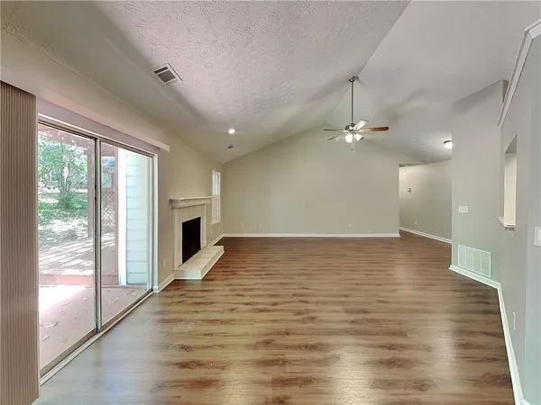 a view of an empty room with window and wooden floor