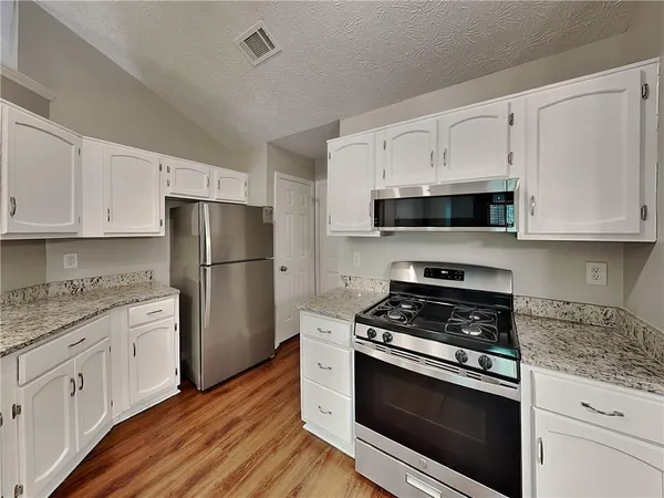 a kitchen with white cabinets and stainless steel appliances