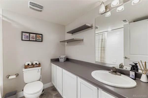 a bathroom with a granite countertop sink mirror vanity and toilet