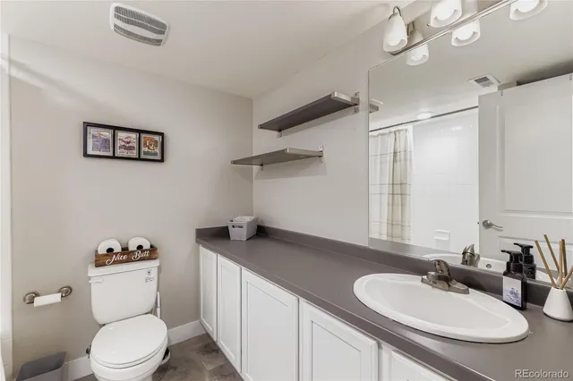 a bathroom with a granite countertop sink mirror vanity and toilet