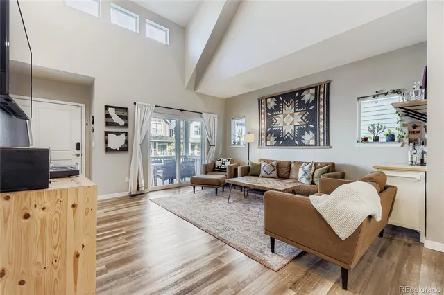 a living room with furniture a flat screen tv and a refrigerator