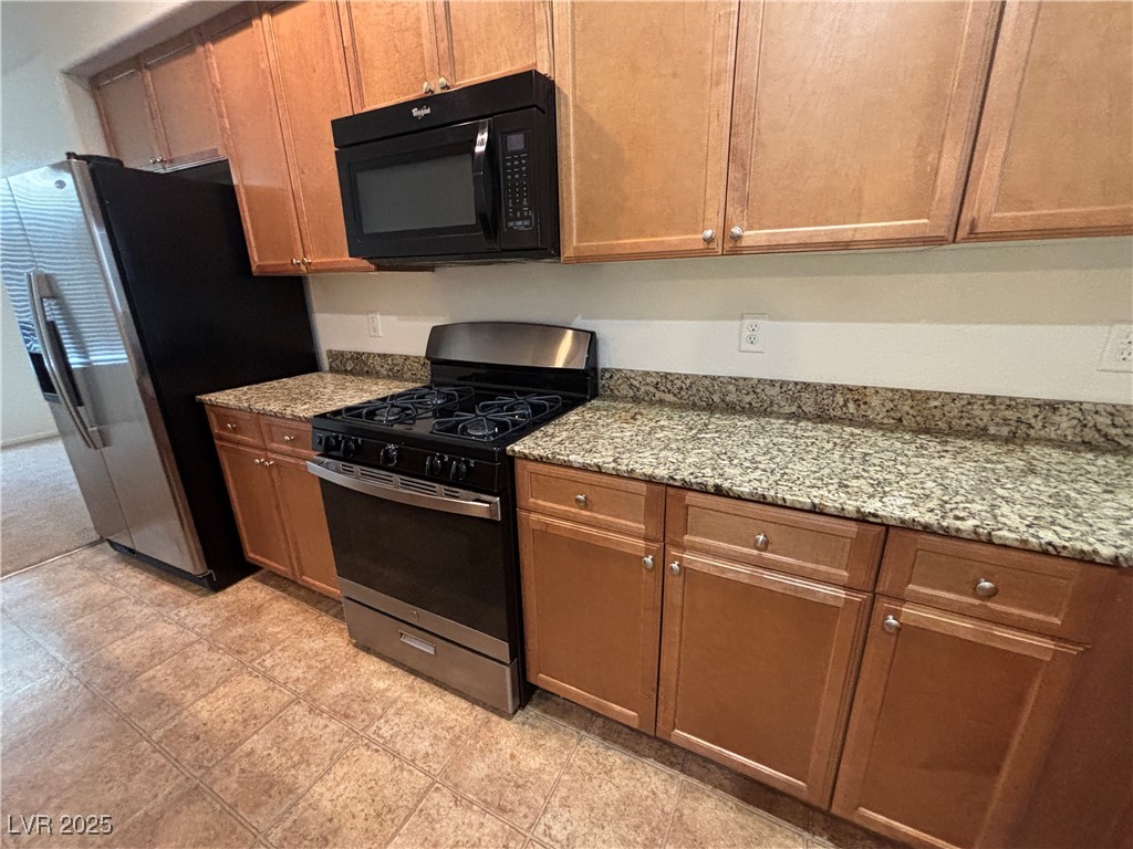 4512 Townwall Street Las Vegas, NV 89115 - Photo 20 of 56 Kitchen featuring appliances with stainless steel finishes, light stone countertops, and brown cabinetry