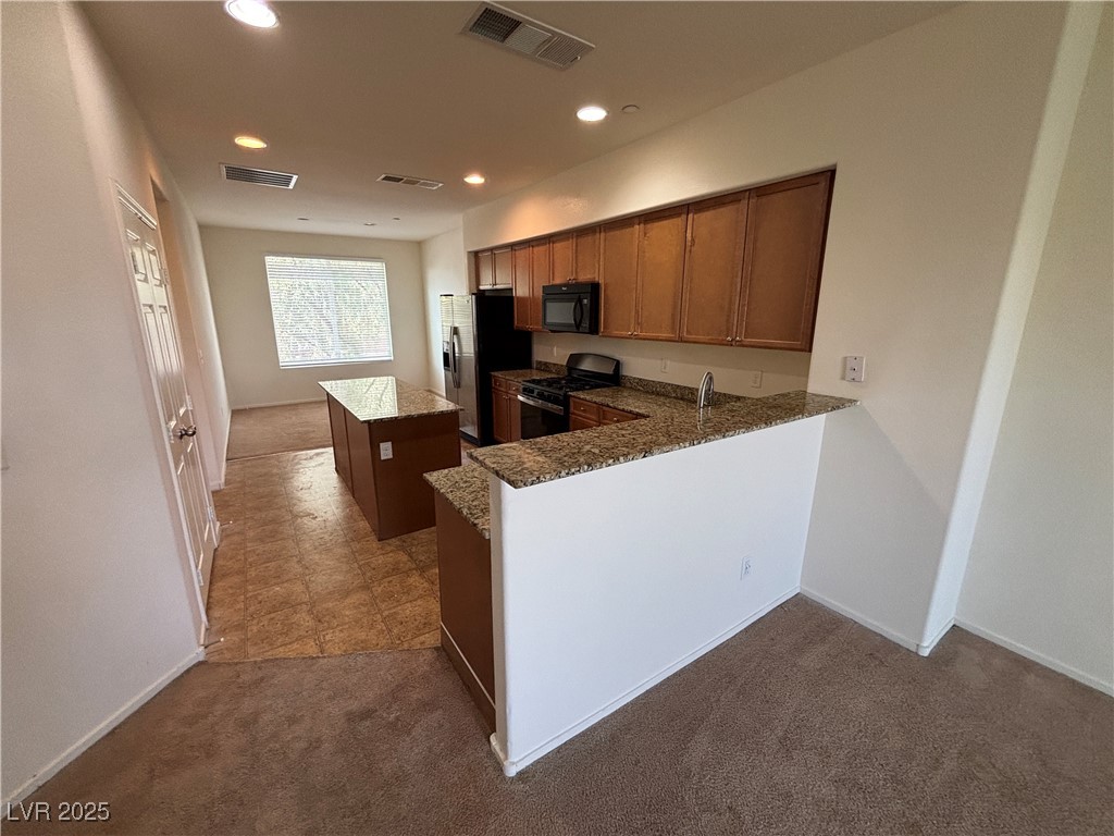 4512 Townwall Street Las Vegas, NV 89115 - Photo 51 of 56 Kitchen with a center island, dark colored carpet, brown cabinetry, black appliances, and recessed lighting