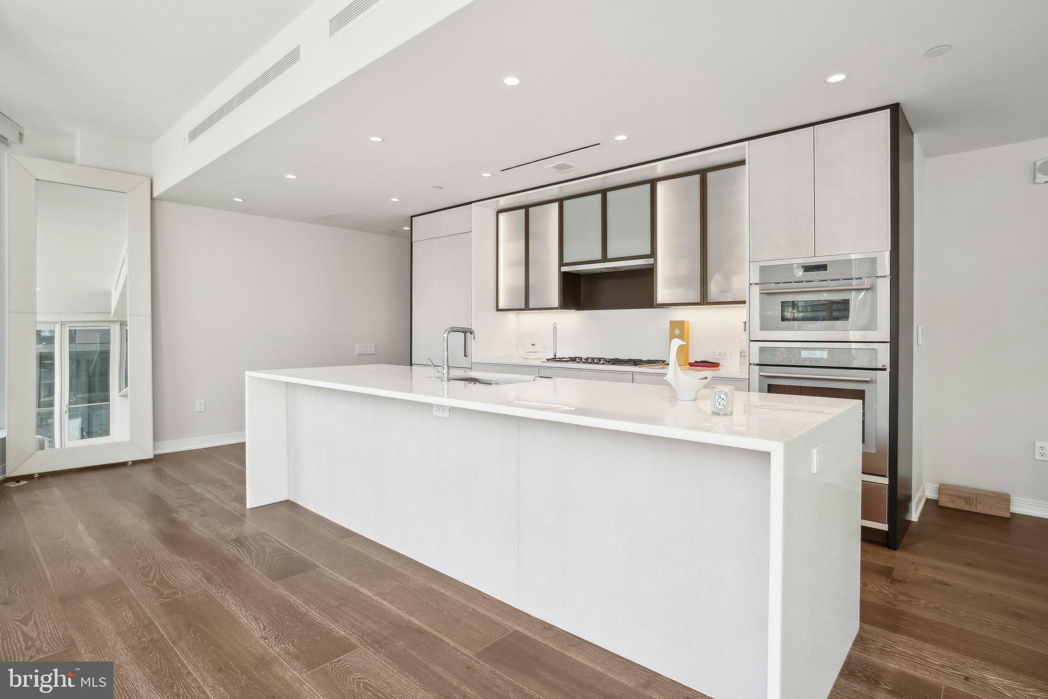 601 Wharf Street Southwest, Unit 213 Washington, DC 20024 - Photo 8 of 23 a large white kitchen with kitchen island a sink stainless steel appliances and cabinets