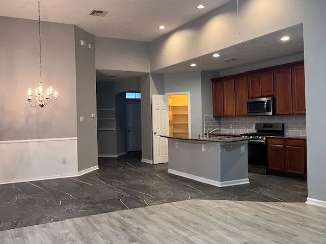 a large kitchen with kitchen island a sink dishwasher a stove and a refrigerator with wooden floor