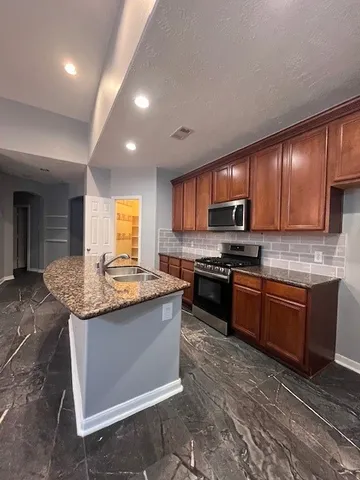 a kitchen with granite countertop stainless steel appliances and wooden cabinets