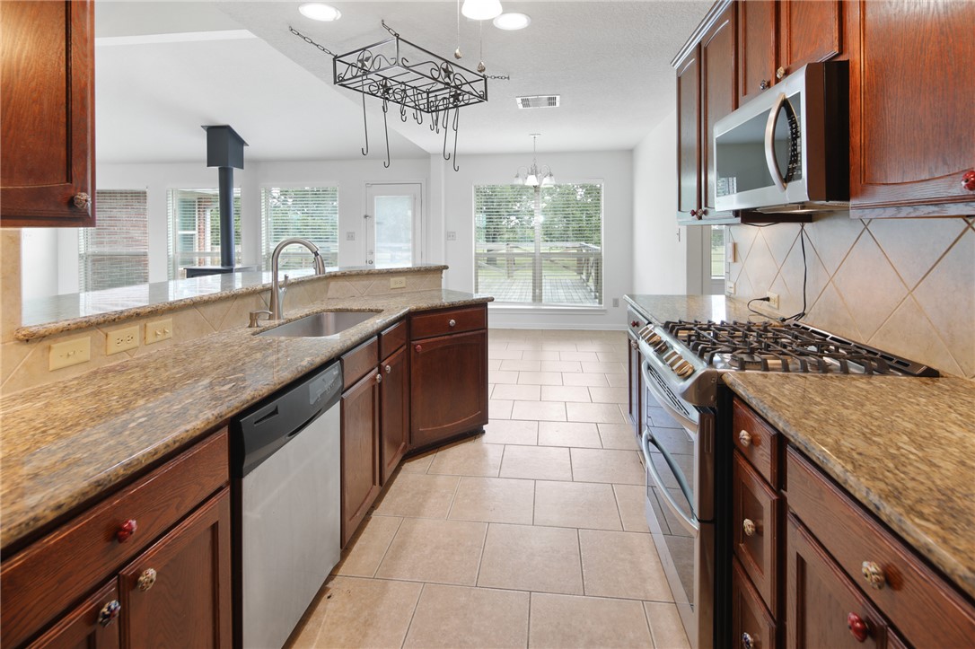7808 Oxford Cemetery Road Madisonville, TX 77864 - Photo 28 of 41 a kitchen with a sink and a stove with a wooden cabinets