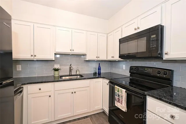 a kitchen with stainless steel appliances granite countertop white cabinets granite counter tops and a wooden floors