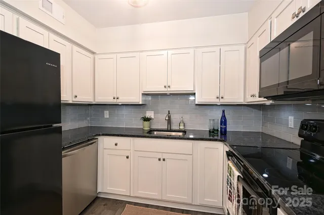 a kitchen with stainless steel appliances granite countertop white cabinets sink and a refrigerator