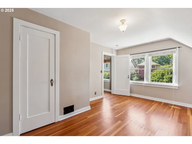 a view of an empty room with window and wooden floor