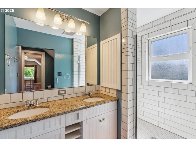 a bathroom with a granite countertop sink a mirror and a shower