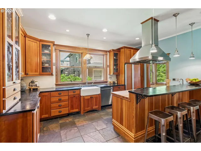 a kitchen with stainless steel appliances kitchen island granite countertop a stove a sink dishwasher and cabinets with wooden floor
