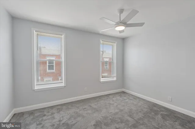 an empty room with windows and ceiling fan