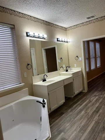 a bathroom with a double vanity sink a mirror and a bathtub