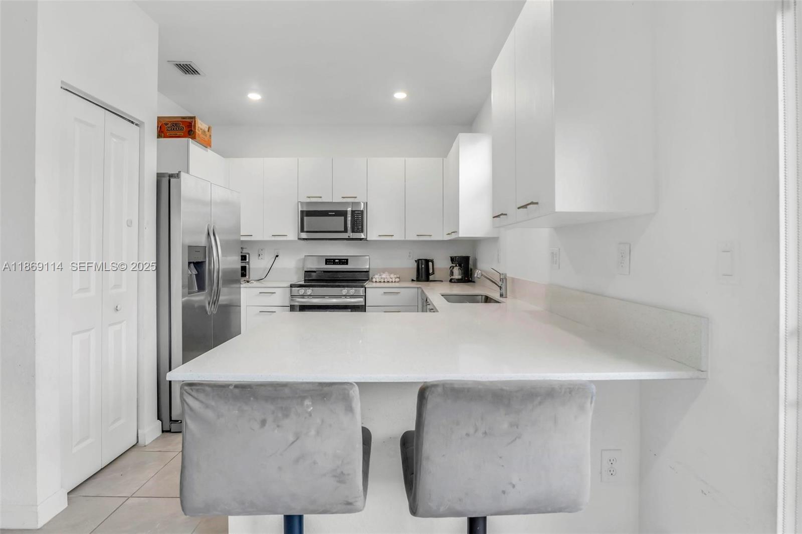 12774 Northwest 22nd Place Miami, FL 33167 - Photo 9 of 32 a kitchen with kitchen island a sink stove and refrigerator