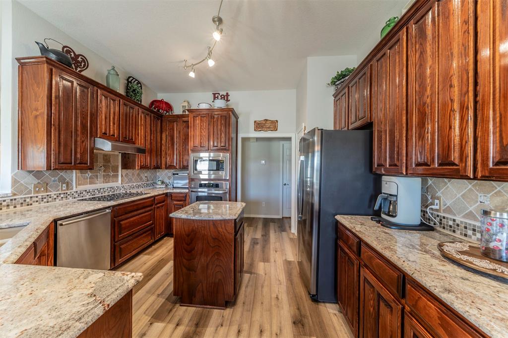11621 Willow Springs Road Fort Worth, TX 76052 - Photo 3 of 35 a kitchen with stainless steel appliances granite countertop a refrigerator a sink dishwasher a stove and a dining table with wooden floor