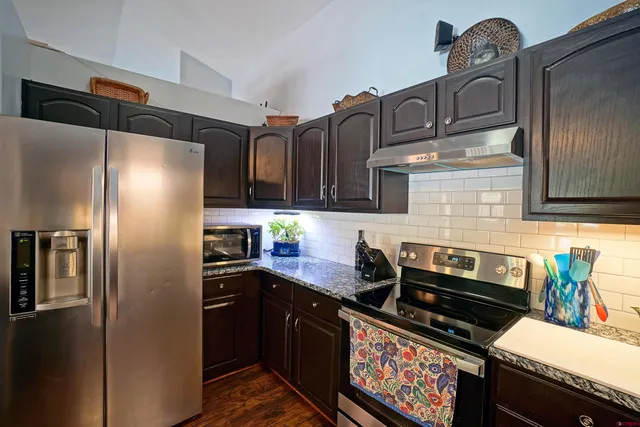 a kitchen with stainless steel appliances granite countertop a refrigerator a stove and a sink