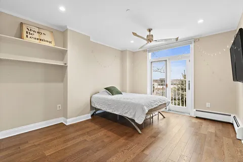 a bedroom with a bed and a large window with wooden floor