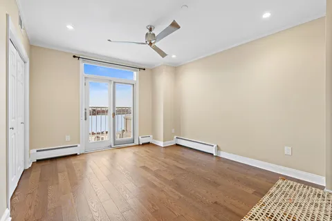 an empty room with wooden floor cabinet and windows