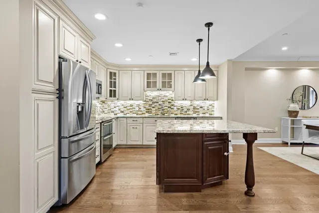 a kitchen with stainless steel appliances kitchen island granite countertop a refrigerator and a sink